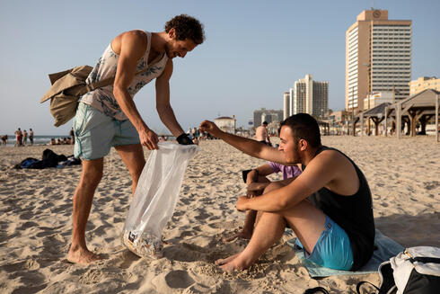 Julian Melcer collects cigarette butts from the shore of the Mediterranean Sea as part of his environmental campaign, at a beach in Tel Aviv 