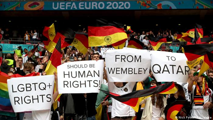 Aficionados al fútbol con banderas alemanas sostienen carteles con un mensaje sobre los derechos humanos en Qatar
